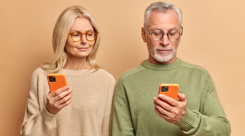 Casal de idosos olha para seus celulares